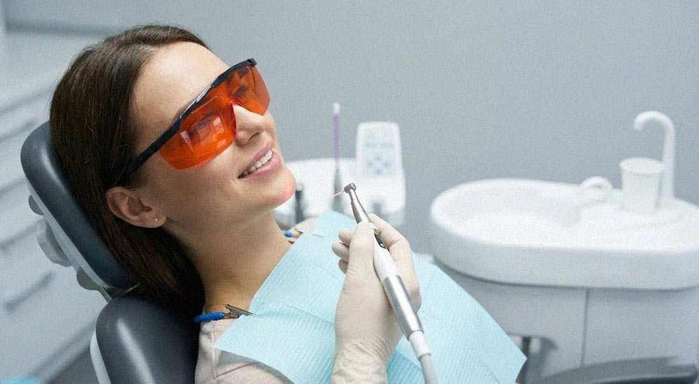 بیمار با عینک محافظ لیزر در حال دریافت درمان لثه بدون درد
